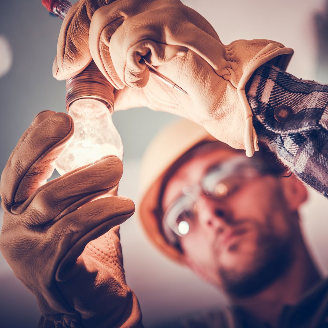 Electrician installs light bulb