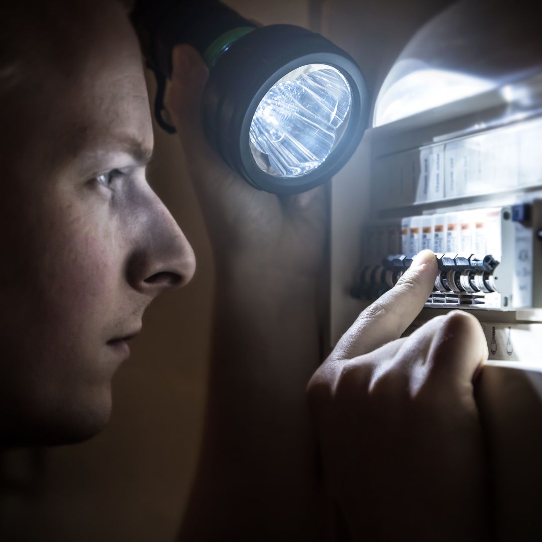 a person looking at a fuse box with a flashlight